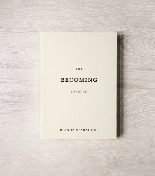 Book titled 'The Becoming Journal' by Bianca Sparacino on a wooden surface