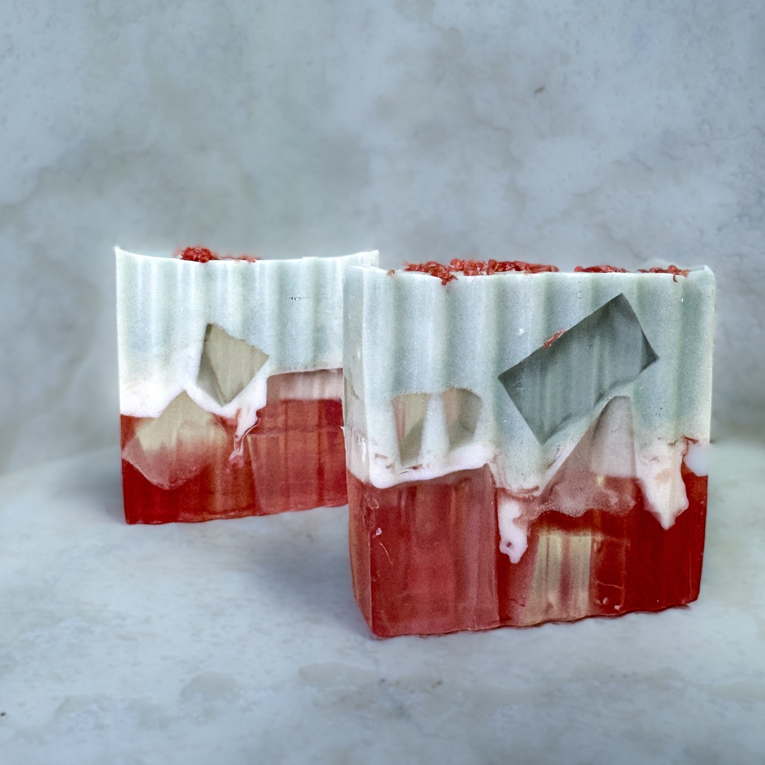 Three bars of soap with a red and white striped pattern on a gray background