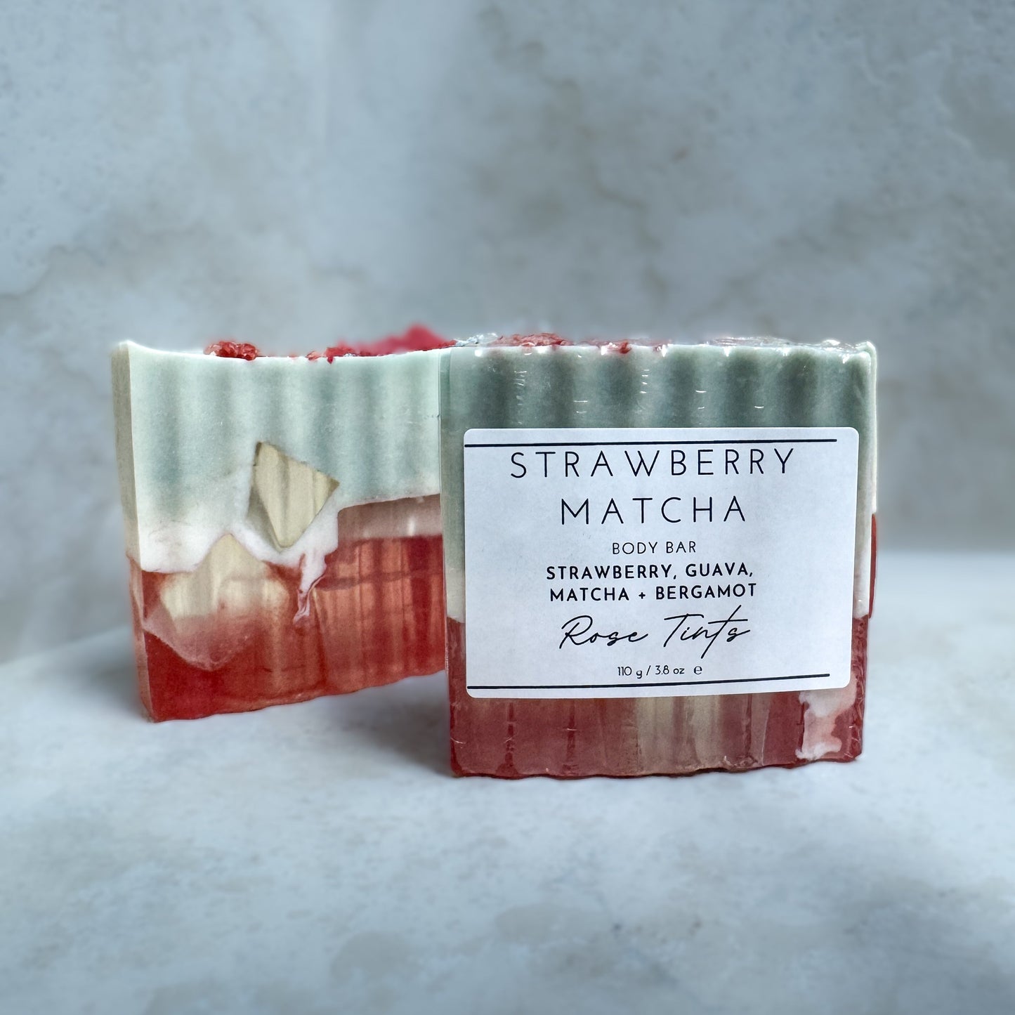 Bar of strawberry matcha soap with a label on a gray background