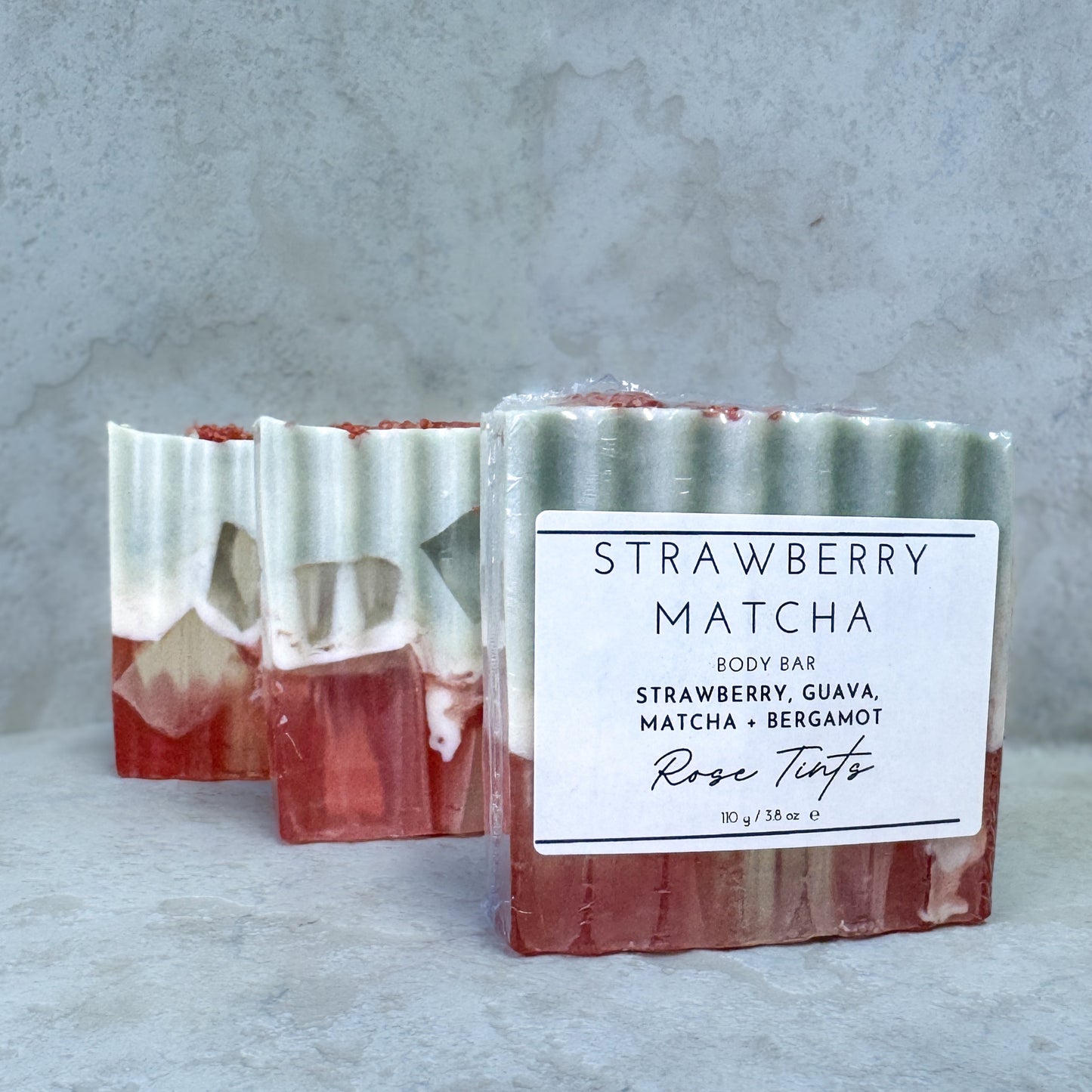 Strawberry Matcha body bar with a label on a gray background