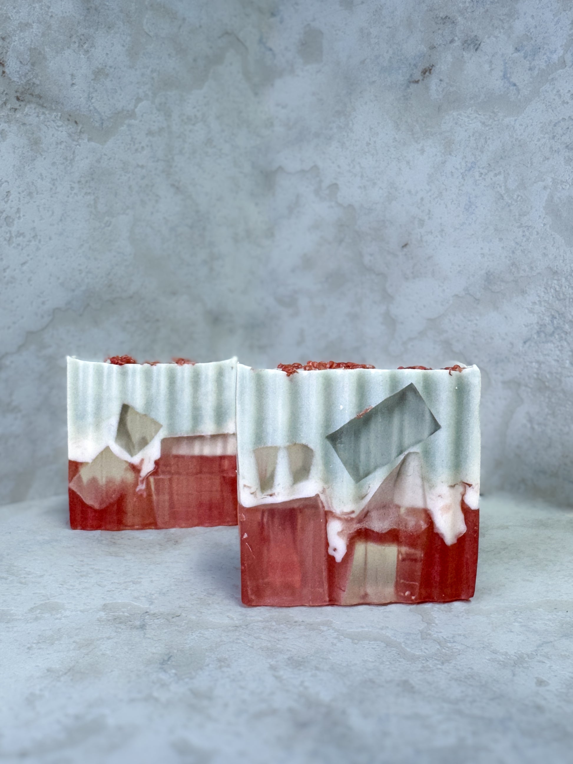 Marbled soap bar with red, white, and gray colors on a textured gray background